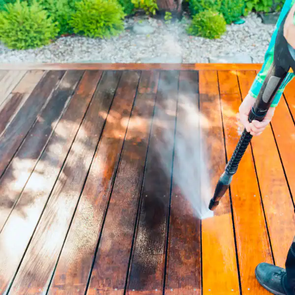 Power washing wooden deck to remove dirt and grime for cleaning.