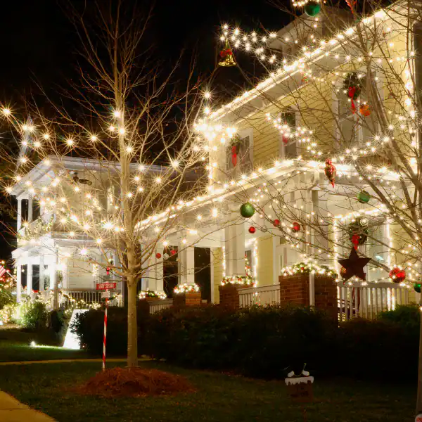 Festively decorated house with Christmas lights and ornaments at night.