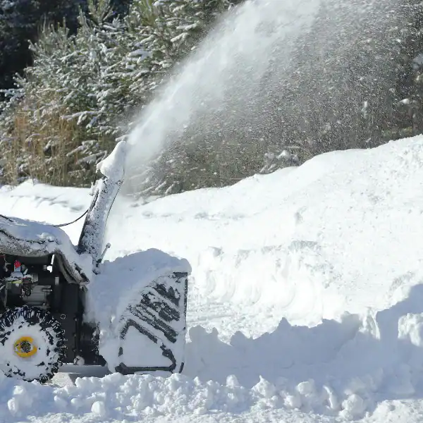 Snow removal with a snow blower in a snowy landscape during winter.