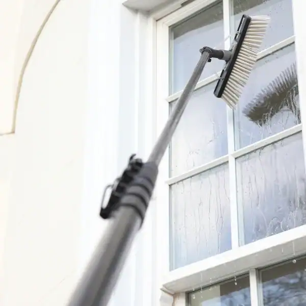 Window cleaning with a squeegee and long handle on a glass window.